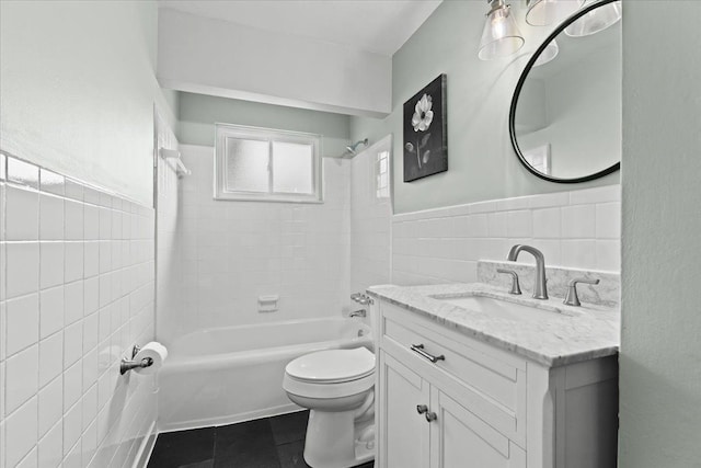 bathroom featuring tile patterned flooring, toilet, vanity, tile walls, and  shower combination