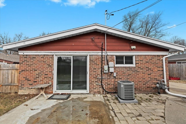 rear view of property featuring a patio area, fence, cooling unit, and brick siding