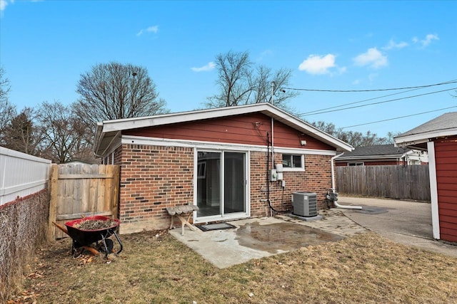 rear view of house with a patio area, a fenced backyard, cooling unit, and brick siding