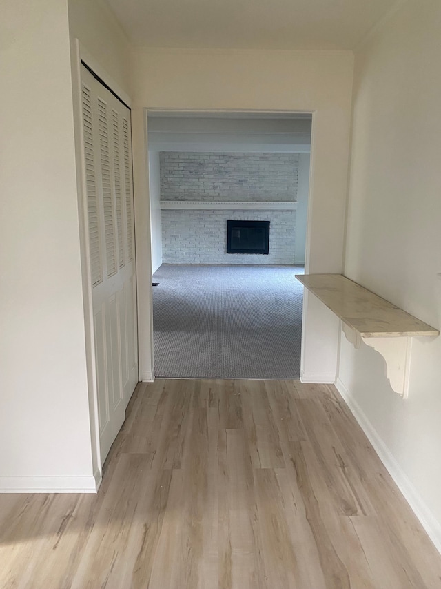 corridor featuring light wood-type flooring and baseboards