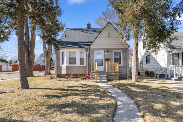 bungalow featuring a shingled roof, a chimney, a front yard, and fence