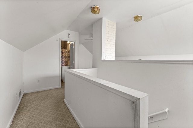 hallway with an upstairs landing, baseboards, carpet, and vaulted ceiling