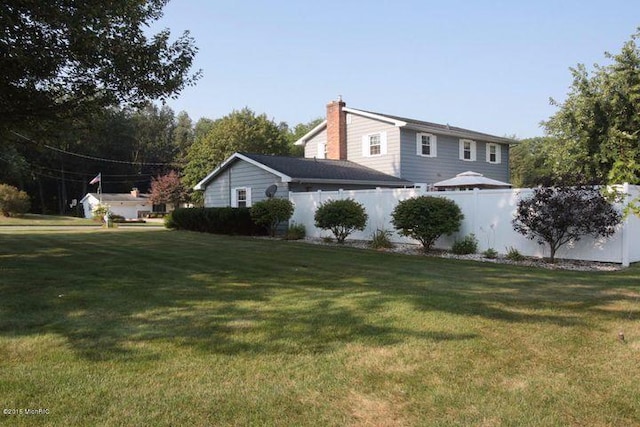 view of home's exterior featuring a lawn, a chimney, and fence