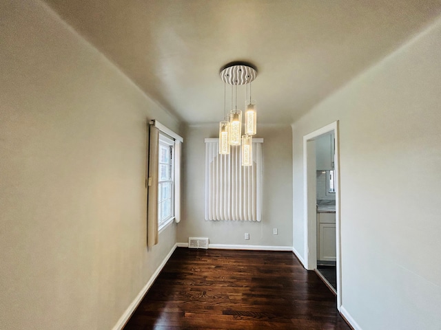 unfurnished dining area with dark wood-style floors, visible vents, and baseboards