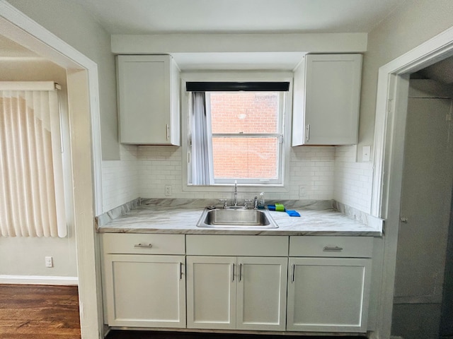 kitchen featuring tasteful backsplash, white cabinetry, dark wood-type flooring, and a sink