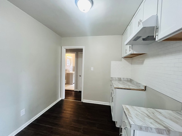 kitchen with light countertops, dark wood-style flooring, decorative backsplash, and under cabinet range hood