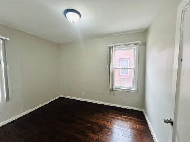 empty room featuring dark wood-style floors and baseboards