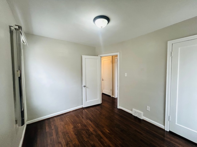 unfurnished bedroom featuring baseboards, visible vents, and dark wood-style flooring