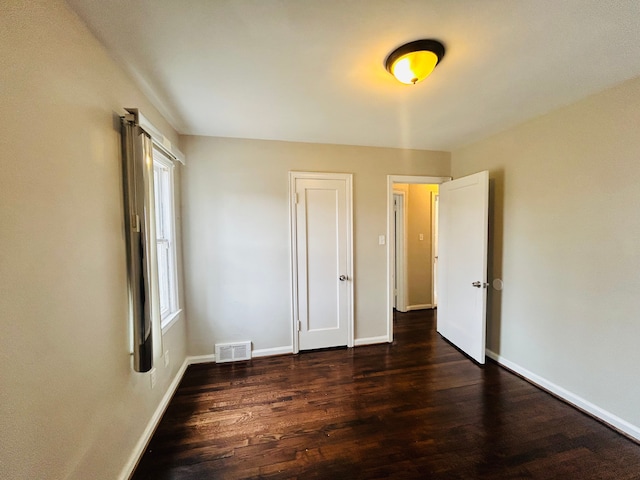 unfurnished bedroom with wood finished floors, visible vents, and baseboards