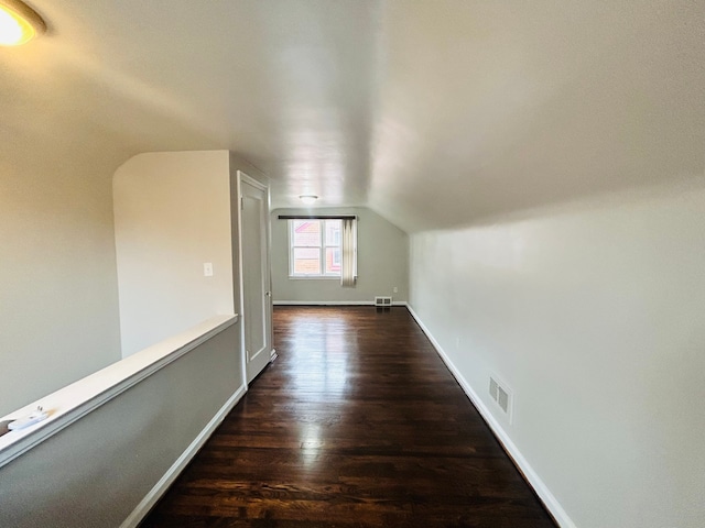 additional living space featuring baseboards, vaulted ceiling, visible vents, and dark wood finished floors