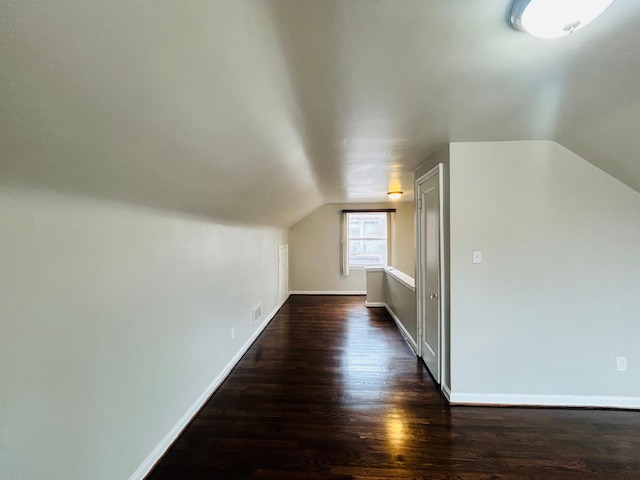 bonus room with lofted ceiling, dark wood-style flooring, visible vents, and baseboards