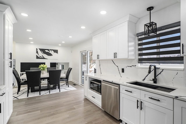 kitchen with appliances with stainless steel finishes, white cabinets, a healthy amount of sunlight, and a sink