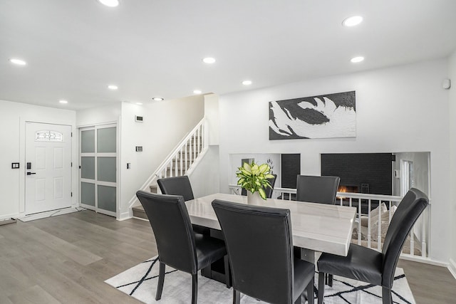 dining room with stairs, a fireplace, wood finished floors, and recessed lighting