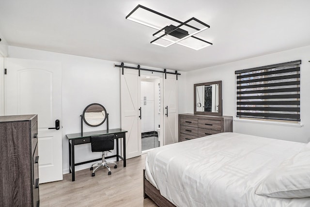 bedroom with light wood-style floors and a barn door