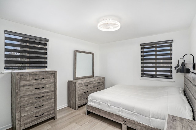 bedroom featuring multiple windows, light wood-type flooring, and baseboards