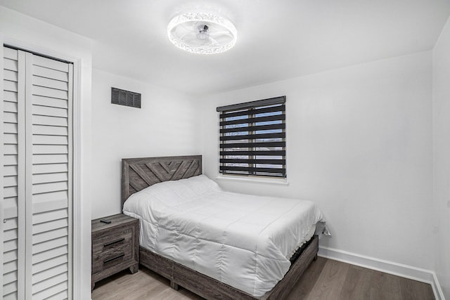 bedroom with wood finished floors, visible vents, and baseboards