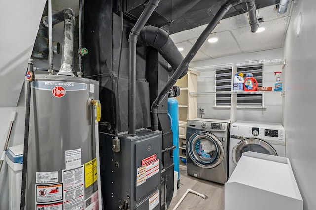 laundry area featuring wood finished floors, gas water heater, and washing machine and dryer