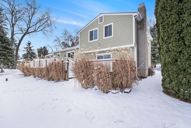 snow covered property with a garage and a chimney