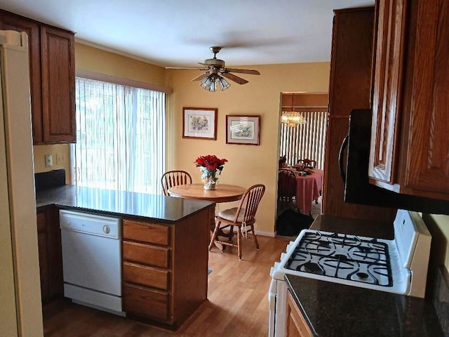 kitchen featuring ceiling fan with notable chandelier, a peninsula, white appliances, wood finished floors, and brown cabinets