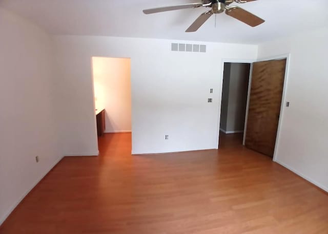 unfurnished room with a ceiling fan, visible vents, and wood finished floors