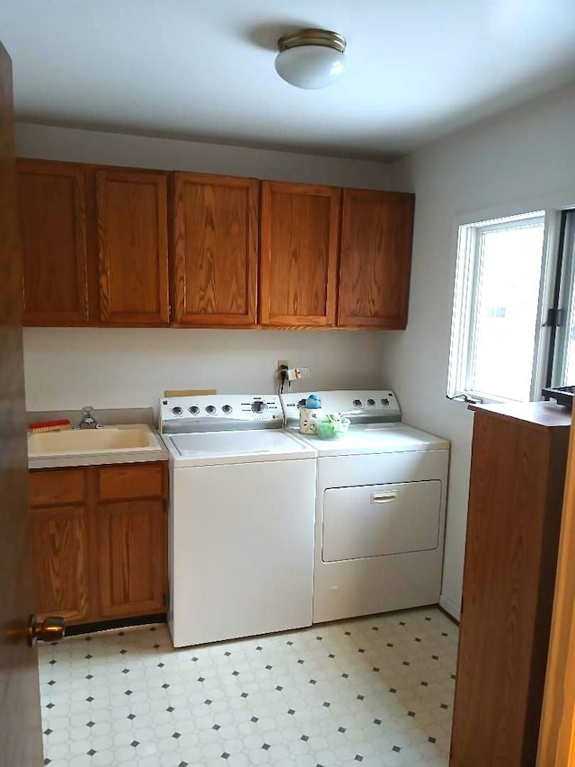 washroom with light floors, washing machine and clothes dryer, a sink, and cabinet space