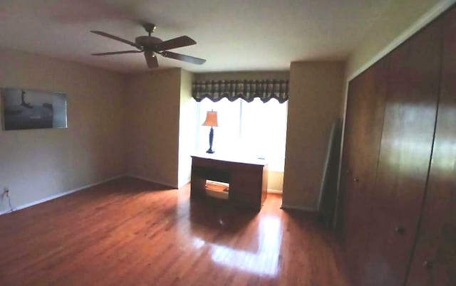 unfurnished bedroom with a ceiling fan, a closet, baseboards, and wood finished floors