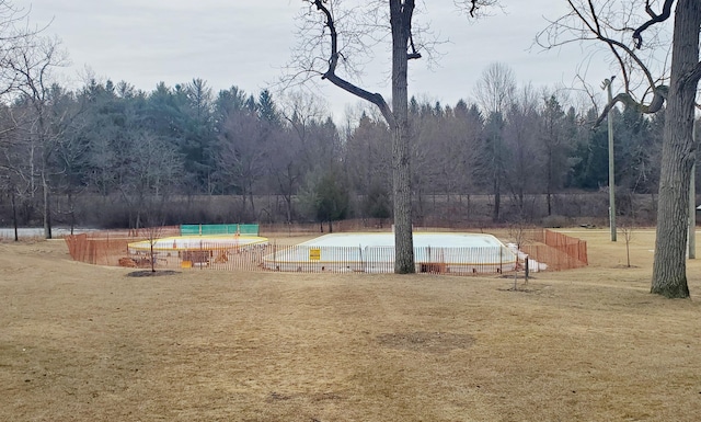 view of community featuring a lawn, fence, and a view of trees