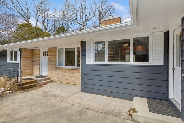 entrance to property featuring a chimney and a patio area