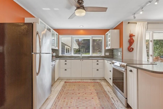 kitchen with stainless steel appliances, glass insert cabinets, backsplash, and a sink