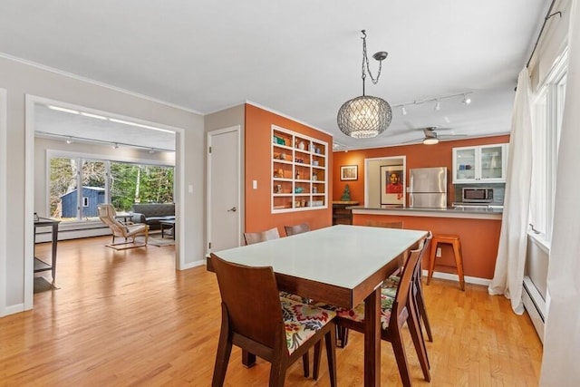 dining room featuring rail lighting, light wood-style flooring, and ornamental molding