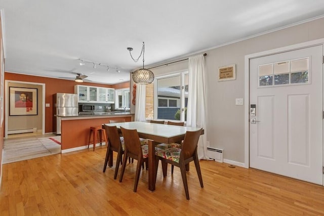 dining area with baseboard heating, light wood-type flooring, a baseboard radiator, and baseboards