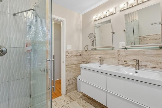 bathroom with double vanity, a shower stall, tile walls, and a sink