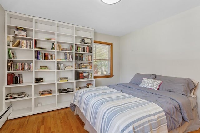 bedroom with baseboard heating and wood finished floors