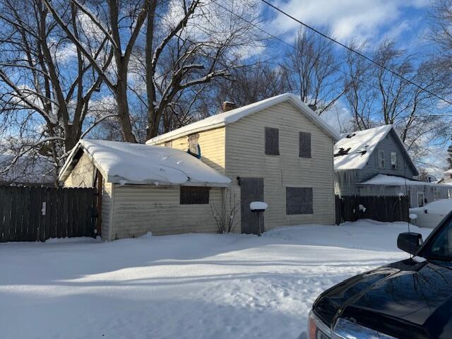 snow covered property featuring a chimney and fence