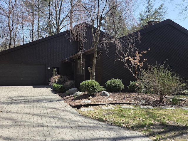 3075 Mineral Springs Trl, Mount Pleasant, MI 48858 - view of side of property featuring a garage, decorative driveway, and a chimney
