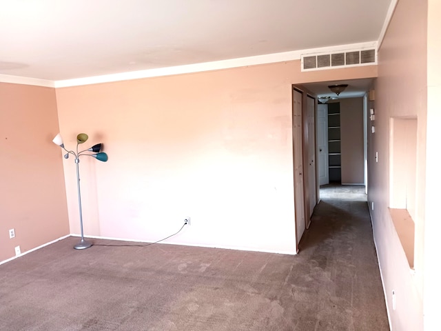 spare room featuring crown molding, visible vents, and dark carpet