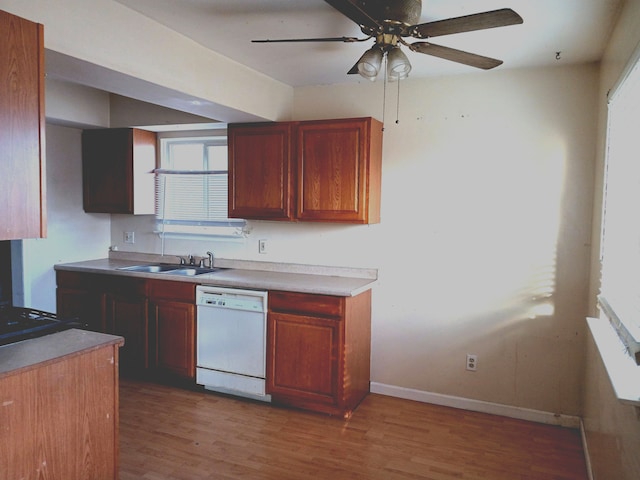 kitchen featuring a ceiling fan, baseboards, light wood-style flooring, a sink, and dishwasher