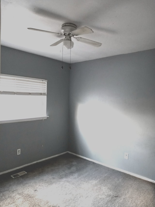 carpeted spare room featuring visible vents, baseboards, and a ceiling fan