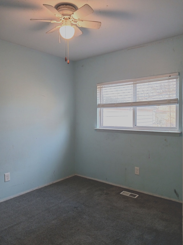 carpeted spare room featuring visible vents and a ceiling fan