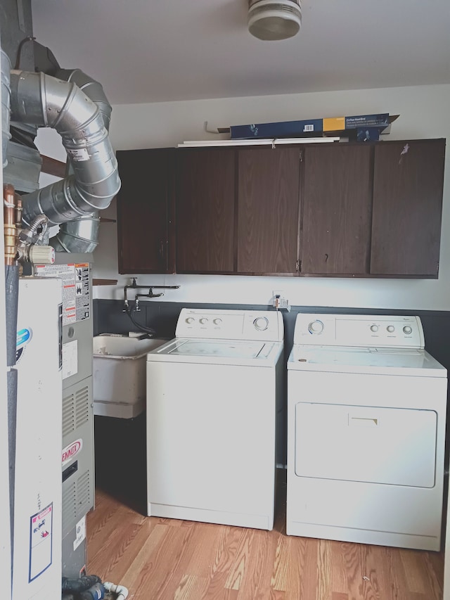 laundry room featuring cabinet space, separate washer and dryer, and light wood-style flooring