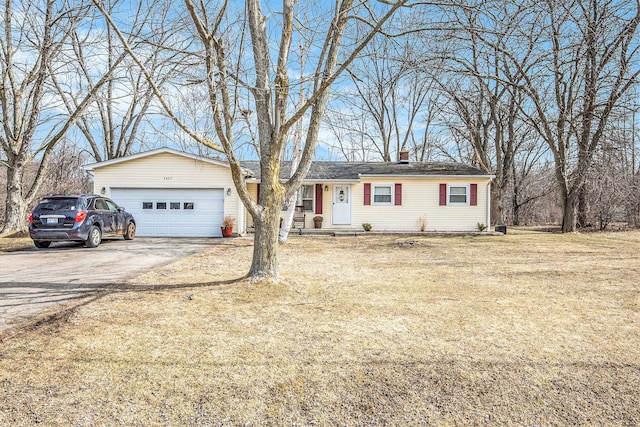 ranch-style home featuring a front lawn, an attached garage, driveway, and a chimney