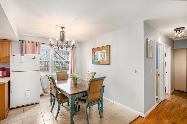 dining room featuring light tile patterned floors, a notable chandelier, and baseboards