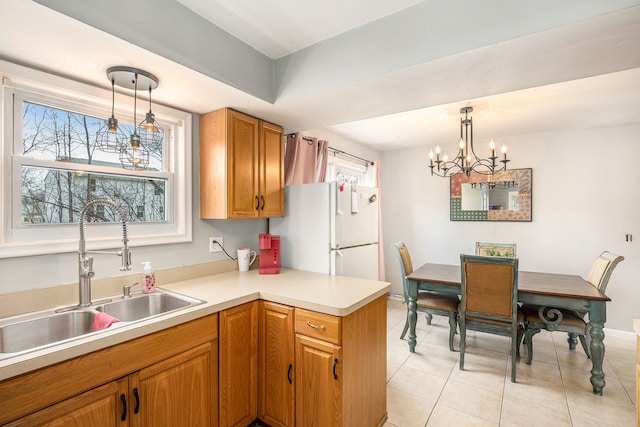 kitchen featuring decorative light fixtures, light countertops, freestanding refrigerator, and a sink