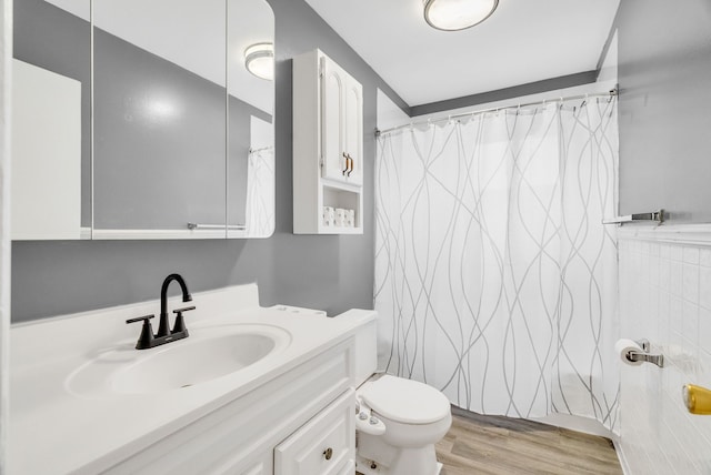 bathroom with toilet, wood finished floors, curtained shower, vanity, and tile walls