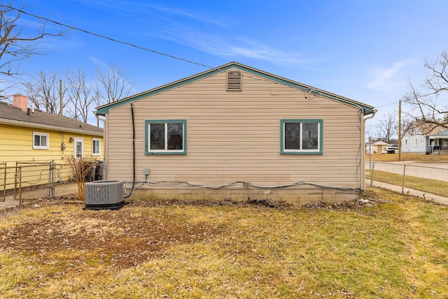 rear view of property featuring central AC, a yard, and fence