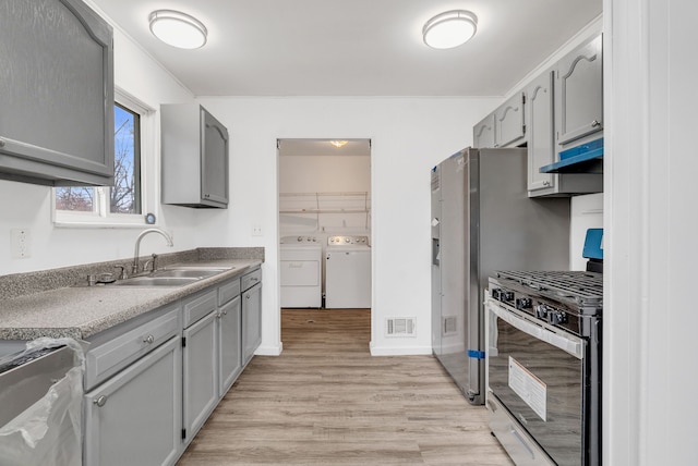 kitchen with washing machine and clothes dryer, visible vents, gray cabinetry, gas stove, and a sink