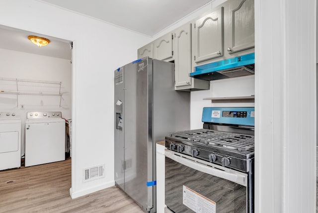 kitchen with washing machine and dryer, exhaust hood, visible vents, light wood-style floors, and appliances with stainless steel finishes