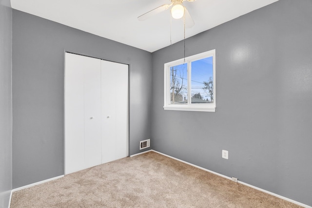 unfurnished bedroom with ceiling fan, a closet, visible vents, and carpet flooring