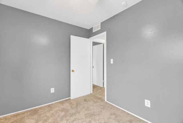 unfurnished room with carpet floors, visible vents, baseboards, and a ceiling fan