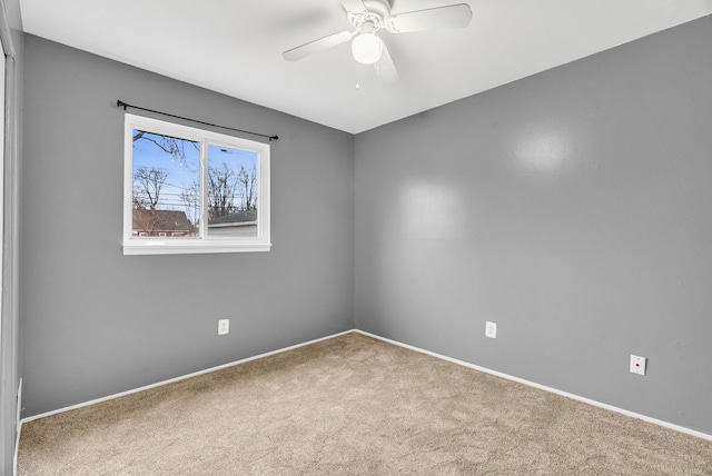 carpeted empty room with a ceiling fan and baseboards